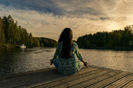 Woman on a dock sitting cross legged and meditating